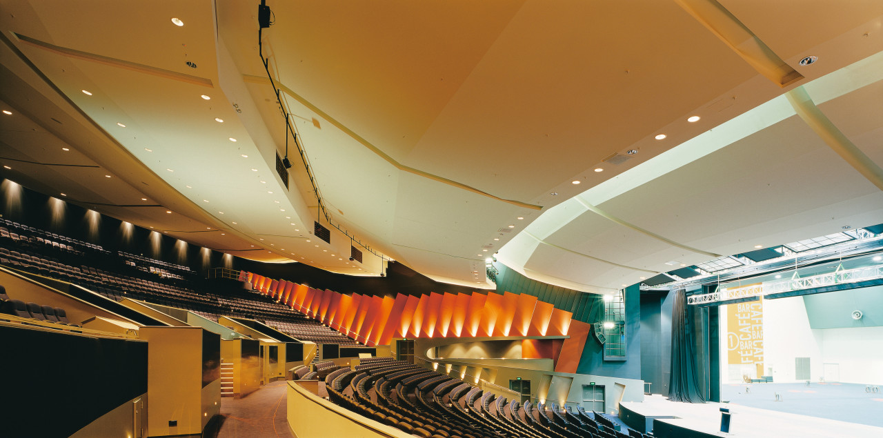Auditorium with tiered seating and orange wall panels. architecture, auditorium, ceiling, daylighting, interior design, performing arts center, brown