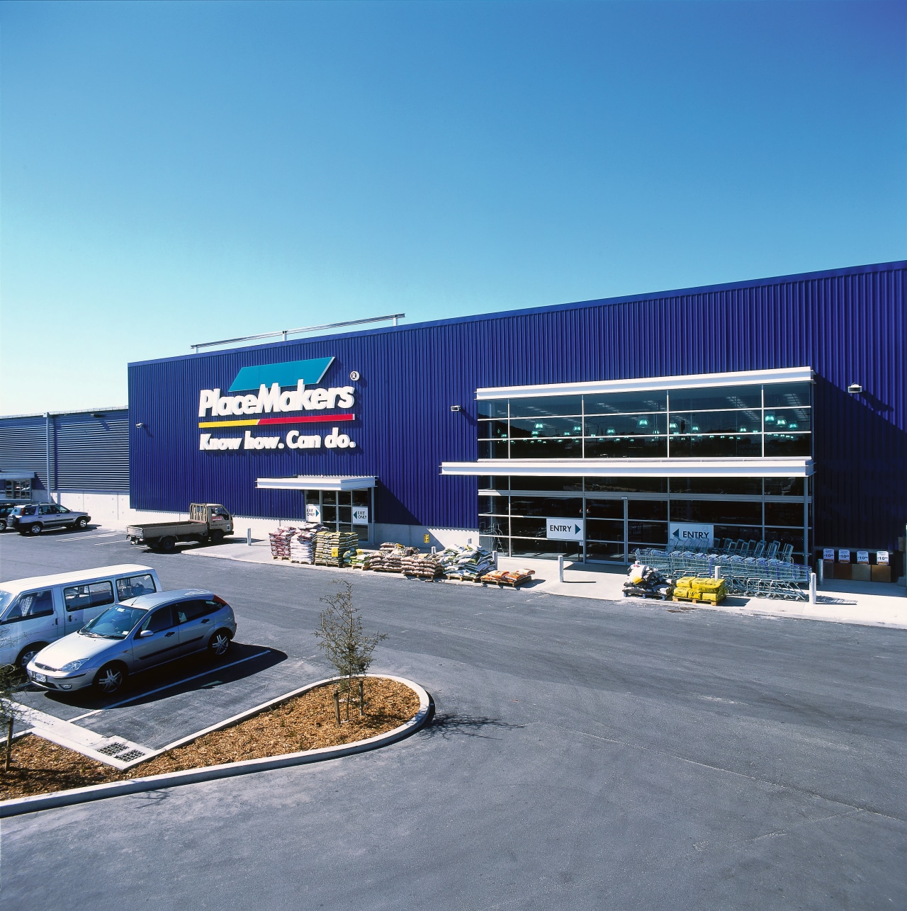 Exterior entrance of Placemakers building showing blue cladding building, commercial building, corporate headquarters, facade, real estate, sky, transport, teal, gray