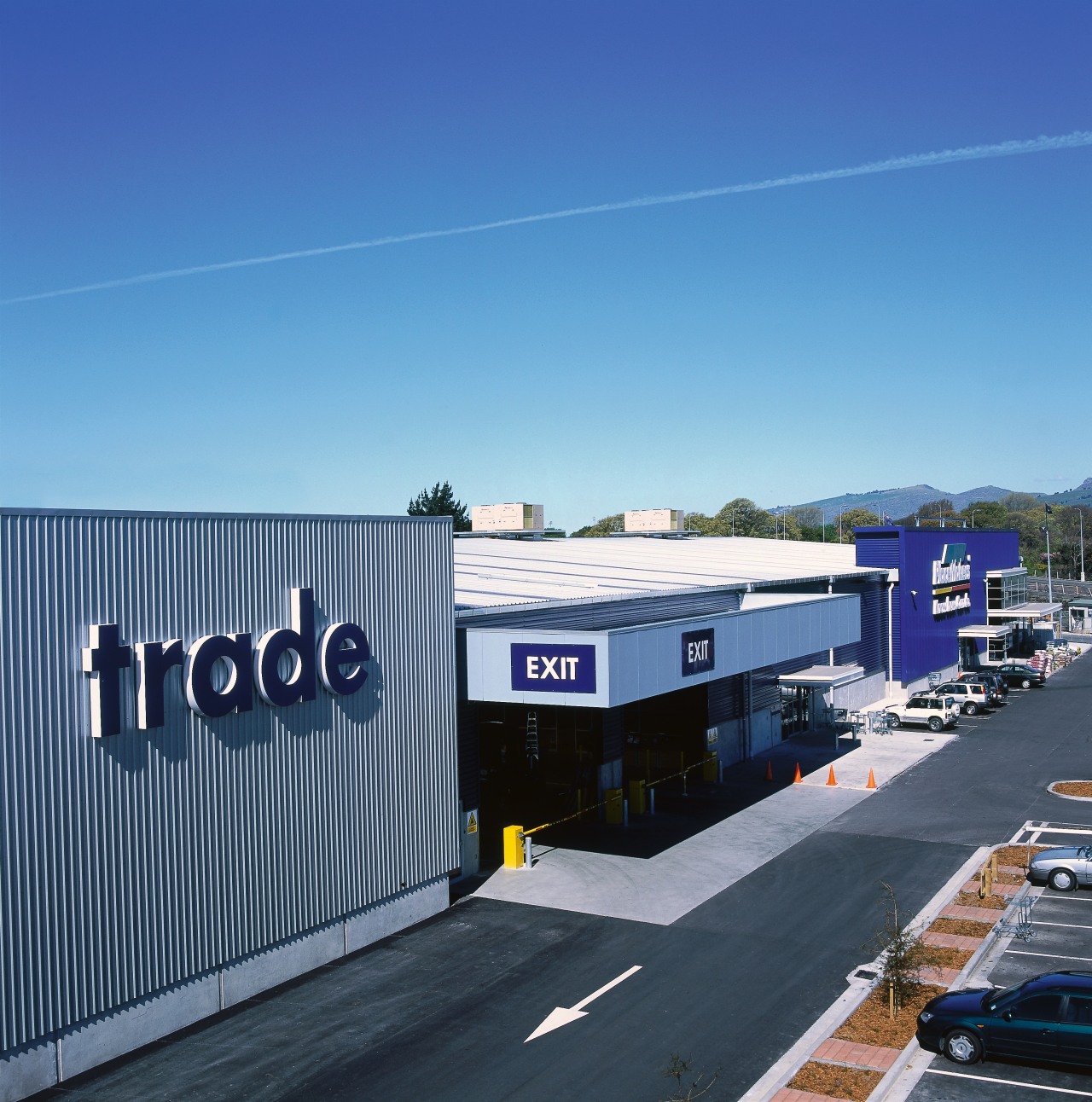 Trade entrance to Placemakers store with grey steel architecture, asphalt, building, corporate headquarters, infrastructure, real estate, road, sky, transport, blue, teal