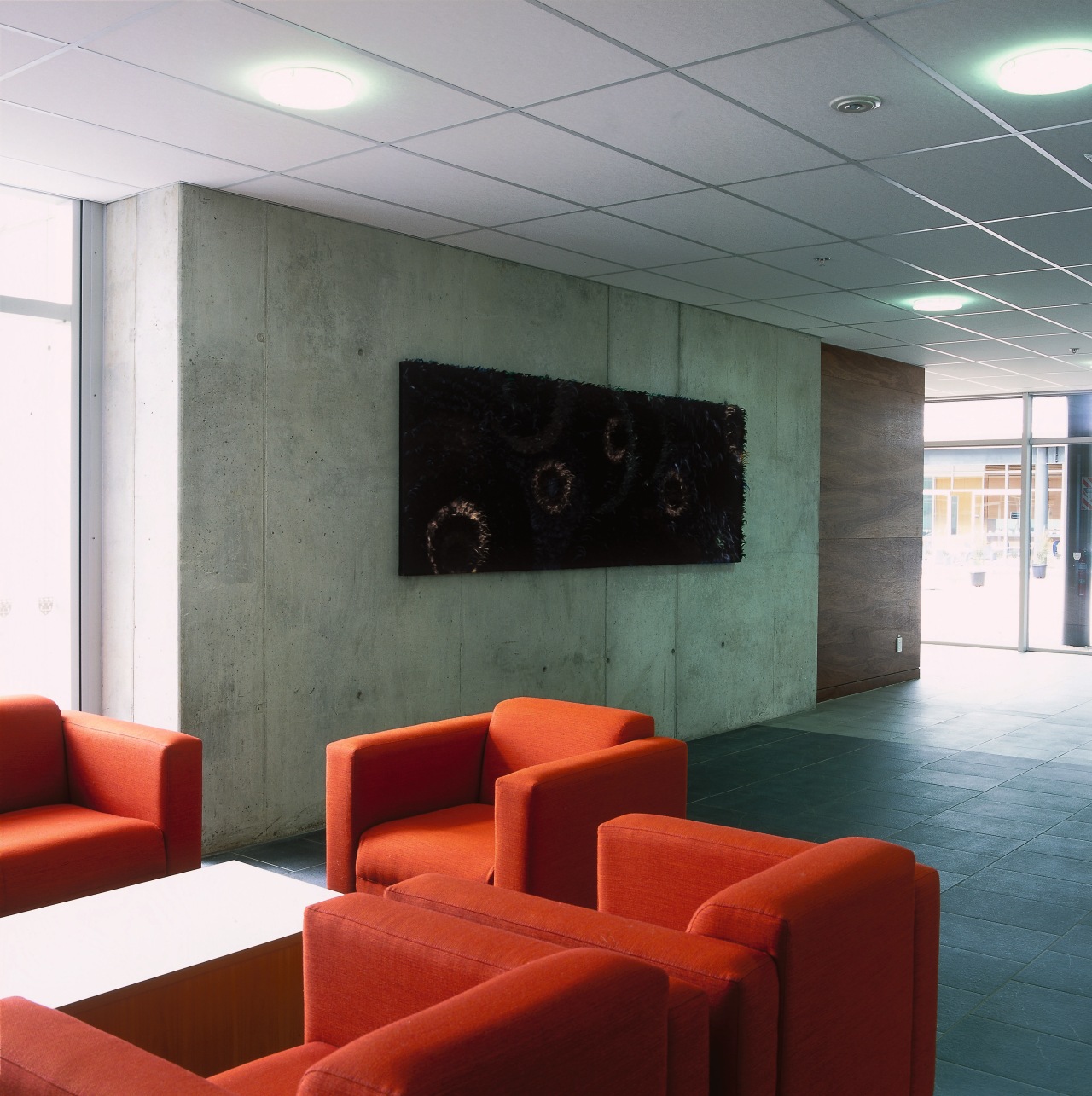 Lobby of building with concrete wall, floor tiles, architecture, ceiling, floor, furniture, interior design, lobby, table, wall, gray