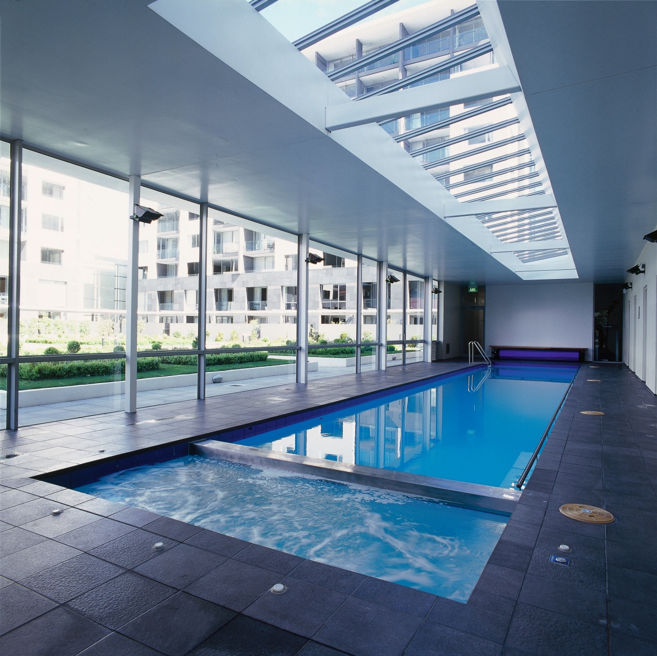 Indoor lap pool and spa with paved surround, apartment, architecture, condominium, corporate headquarters, daylighting, daytime, leisure, leisure centre, property, real estate, swimming pool, water, blue, gray