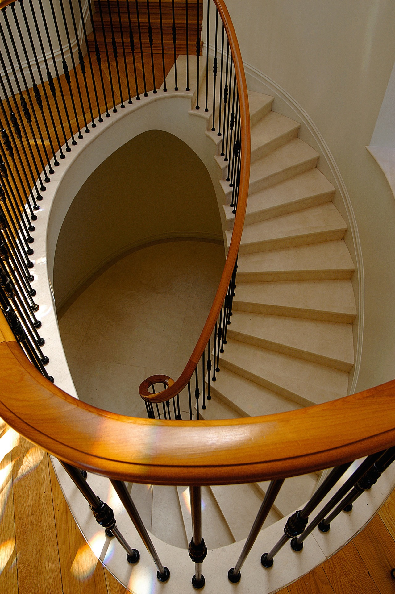 View looking down curved stairway with marble steps, architecture, baluster, daylighting, furniture, handrail, line, spiral, stairs, wood, brown