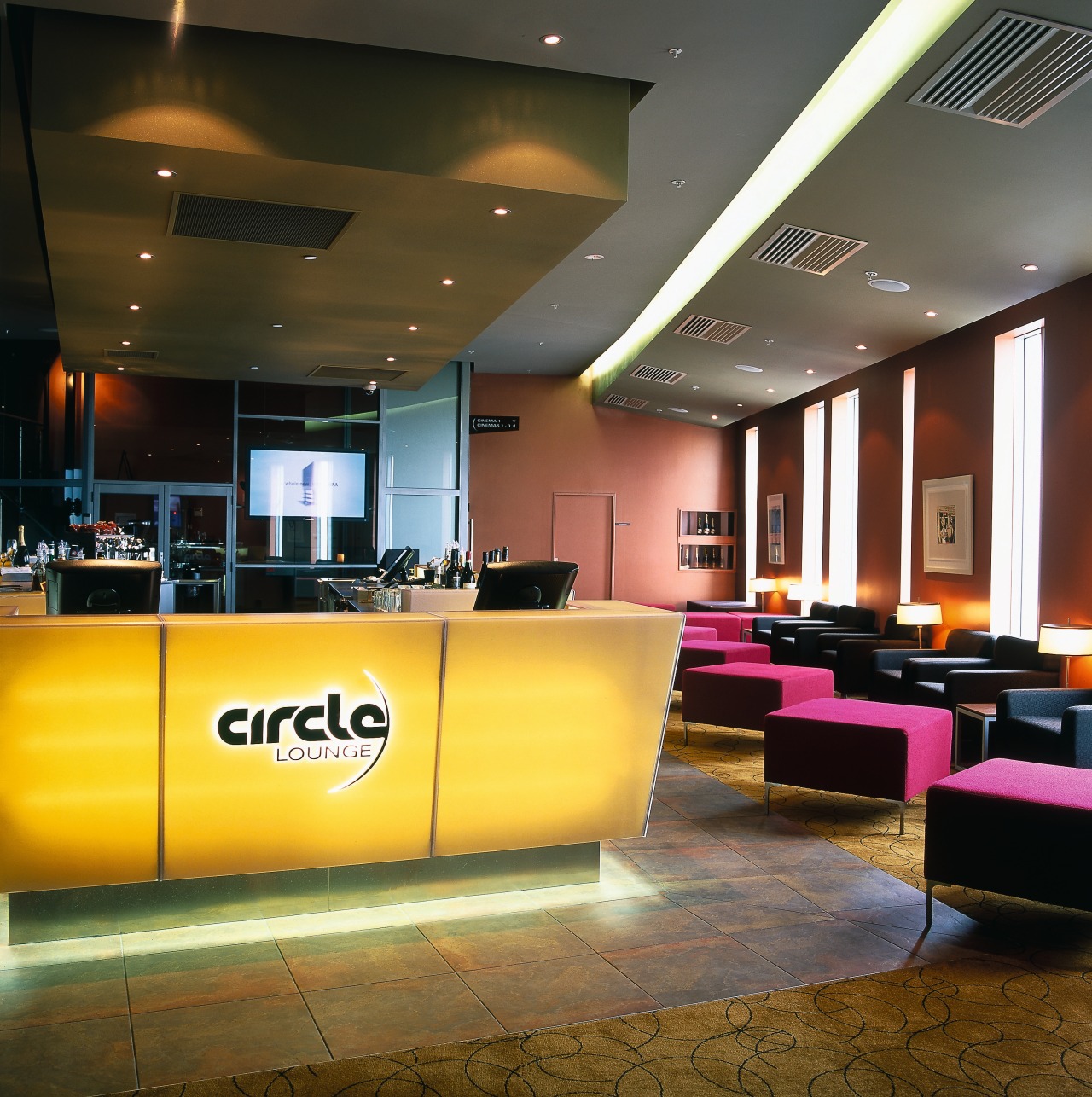 Bar area in cinema complex with yellow cabinetry, ceiling, interior design, lighting, lobby, brown