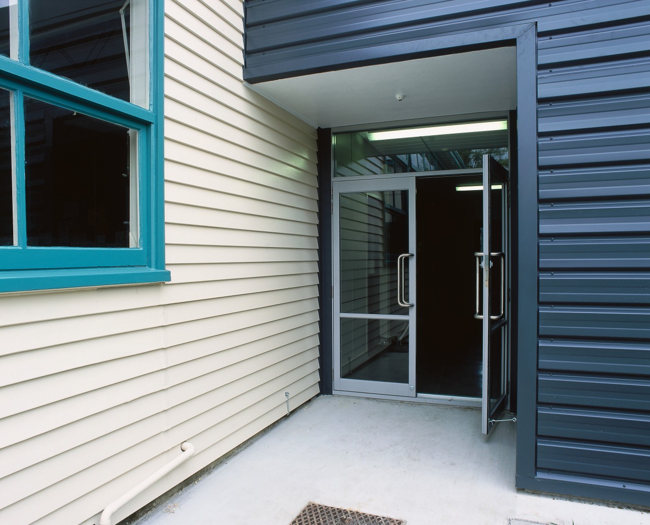 Exterior of school building with white weatherboards, and door, facade, home, house, property, real estate, siding, window, white, black