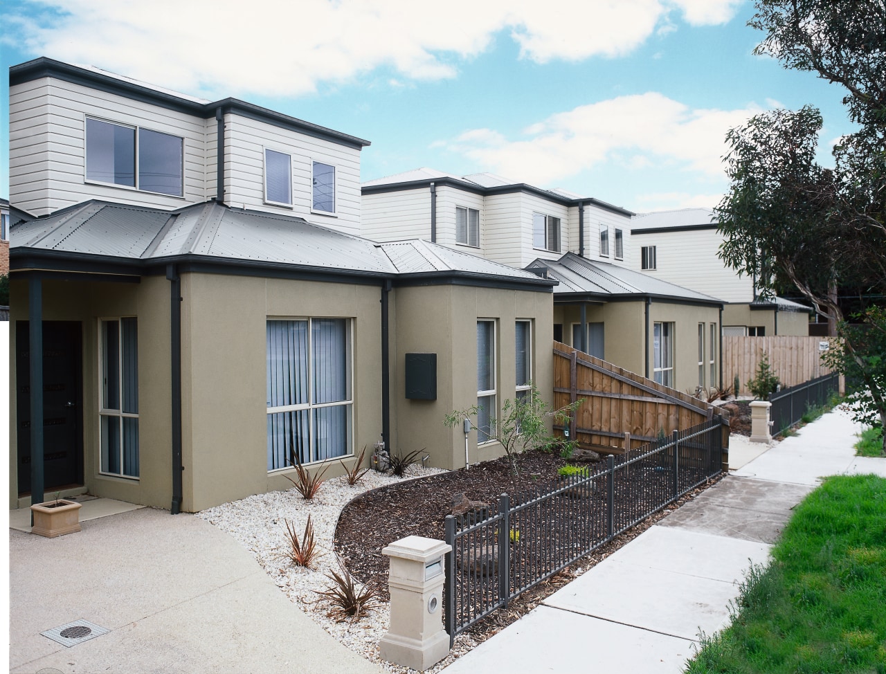Exterior of townhouses with tan coloured cladding on cottage, elevation, estate, facade, home, house, neighbourhood, property, real estate, residential area, siding, suburb, window, yard, white