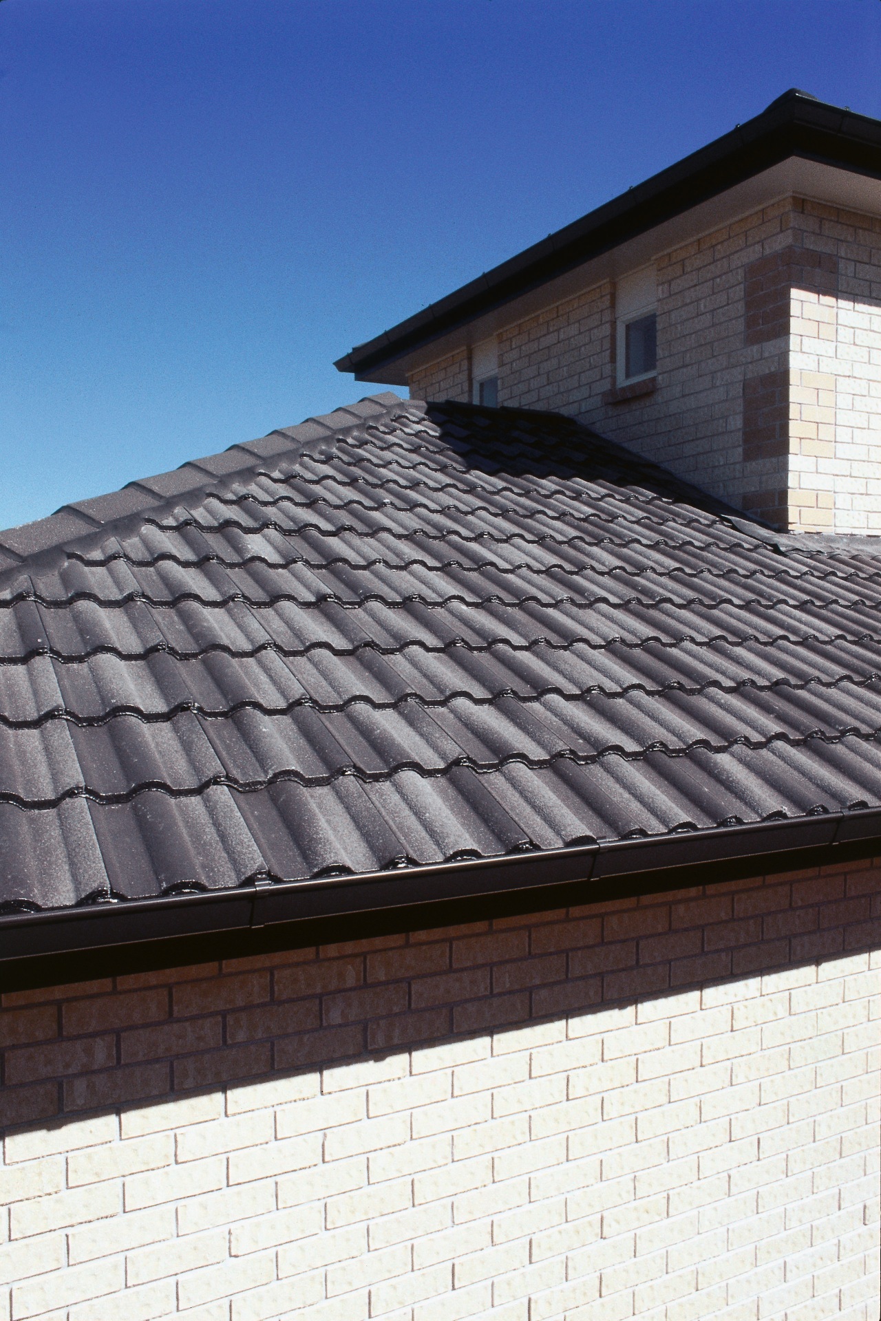 Closeup of grey concrete roof tiles. daylighting, facade, outdoor structure, roof, siding, sky, wall, window, black