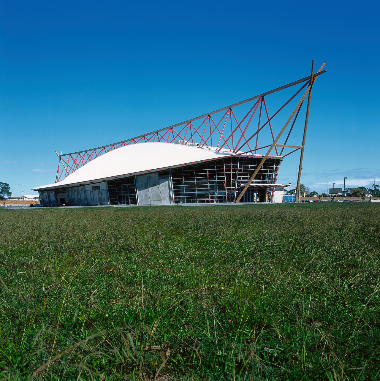 A view of a large boat shaped building, architecture, field, grass, roof, rural area, shed, sky, structure, blue, green