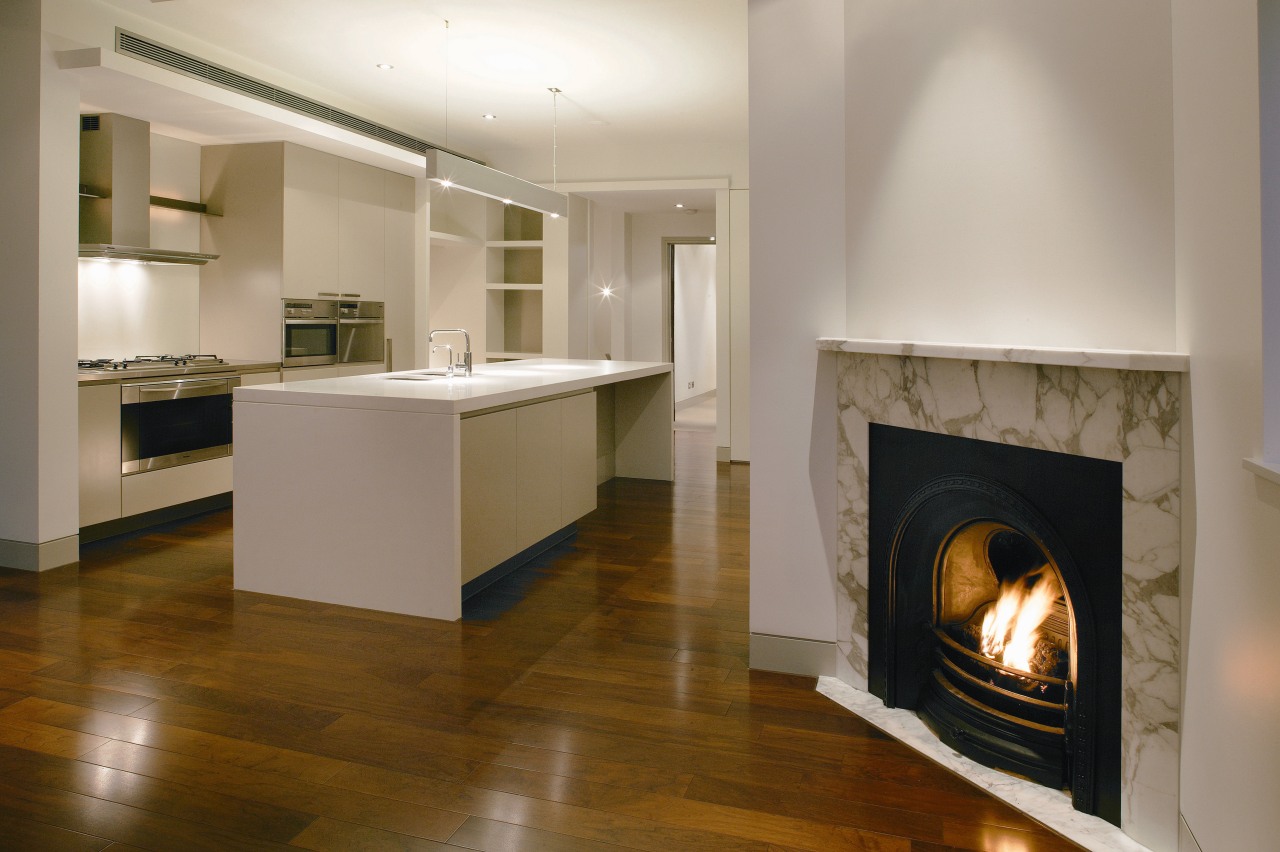 A view of a fireplace surrounded by marble, fireplace, floor, flooring, hardwood, hearth, home appliance, interior design, wood flooring, gray, brown