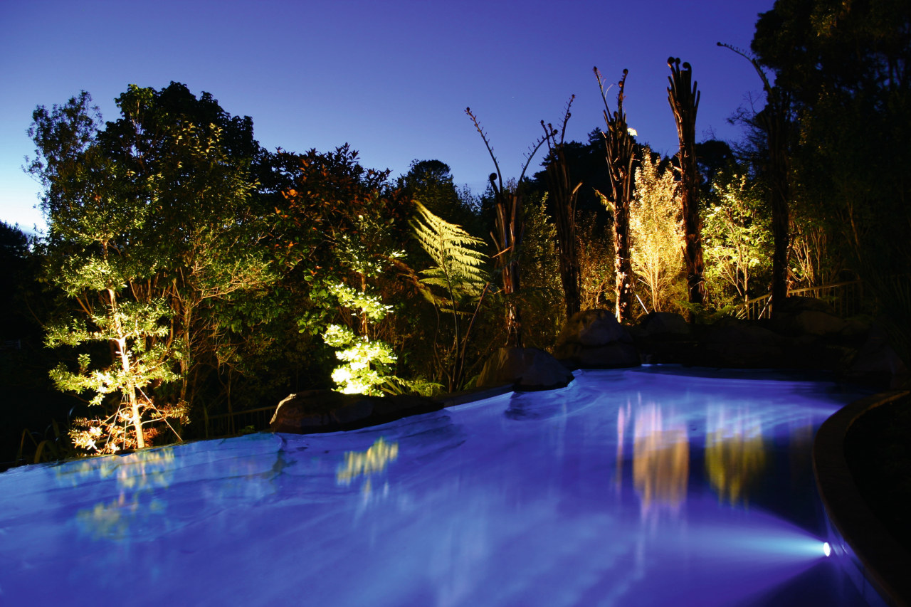 Outdoor pool with blue lighting and trees lit body of water, evening, lake, landscape, landscape lighting, light, lighting, nature, night, reflection, river, sky, tree, water, water feature, watercourse, wilderness, blue