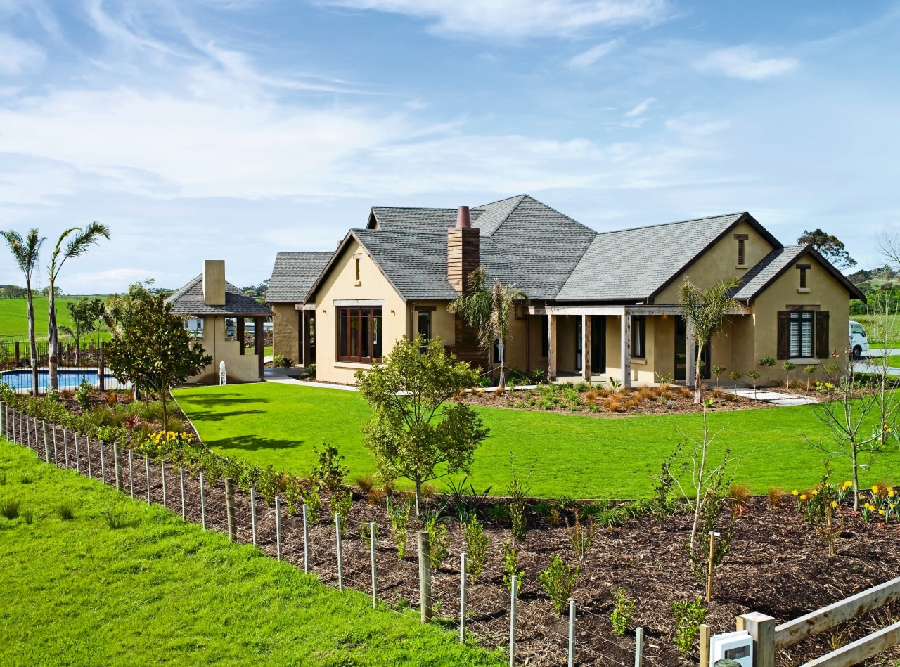 view of the house featuring plastered and lime cottage, estate, facade, farm, farmhouse, fence, field, grass, home, house, land lot, landscape, landscaping, lawn, outdoor structure, plantation, property, real estate, residential area, roof, rural area, sky, tree, yard, white