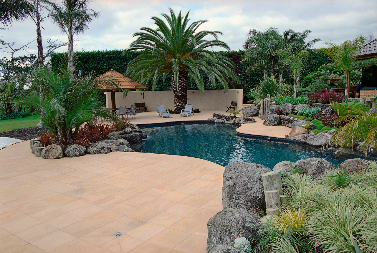 view of the lush outdoor area featuring tuscan arecales, backyard, estate, landscape, landscaping, leisure, outdoor structure, palm tree, plant, property, real estate, resort, swimming pool, water feature, yard, orange
