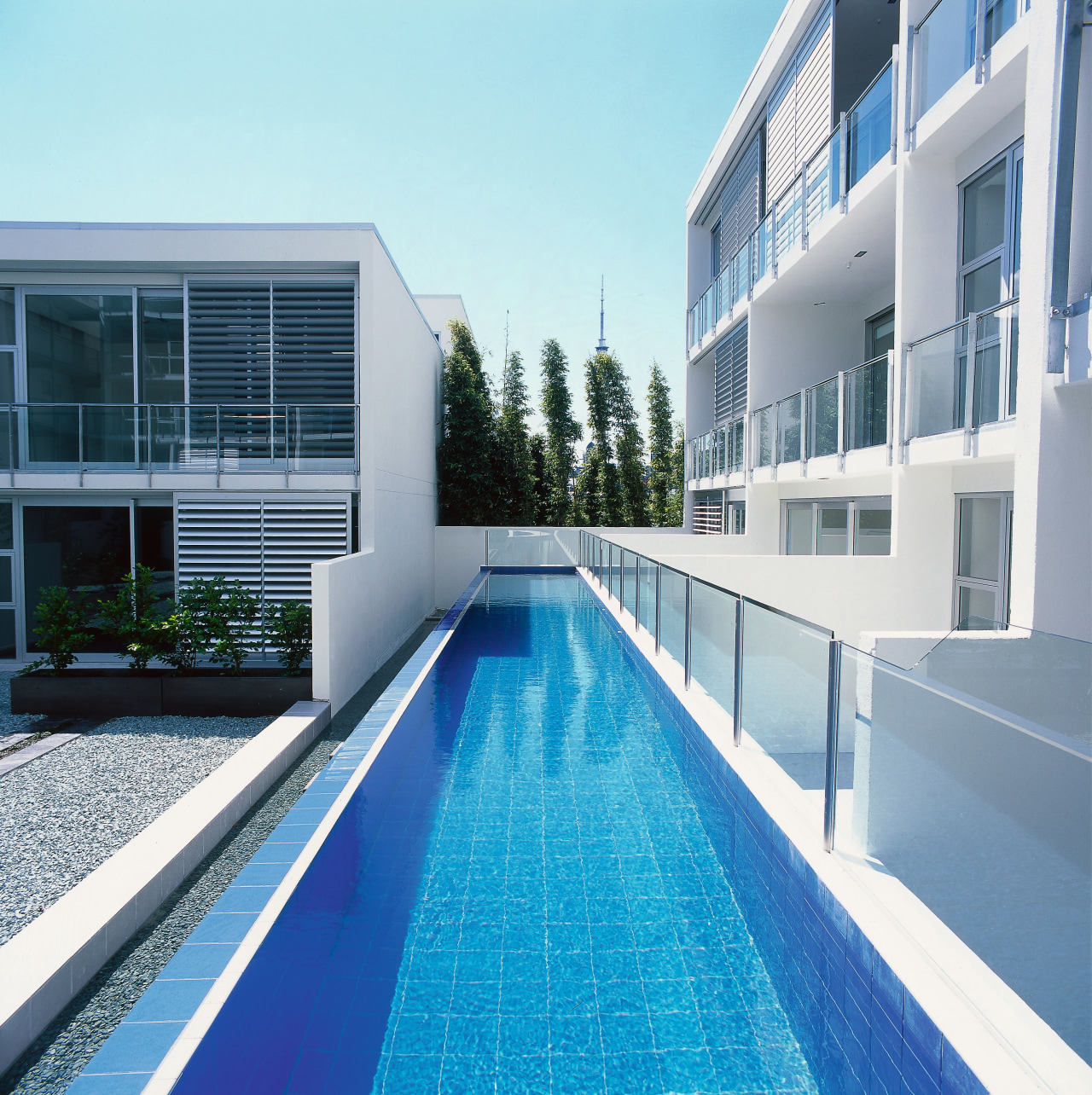 An exterior view of the swimming pool area. apartment, architecture, building, condominium, corporate headquarters, estate, facade, house, leisure, leisure centre, property, real estate, residential area, swimming pool, water, white, teal