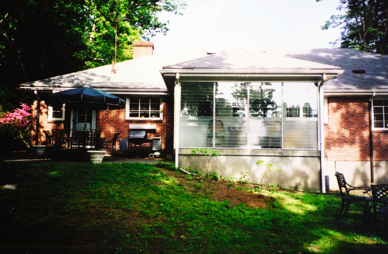 as the enclosed porch at the rear was backyard, cottage, home, house, lighting, outdoor structure, porch, property, real estate, residential area, roof, shed, siding, tree, window, yard, black, white
