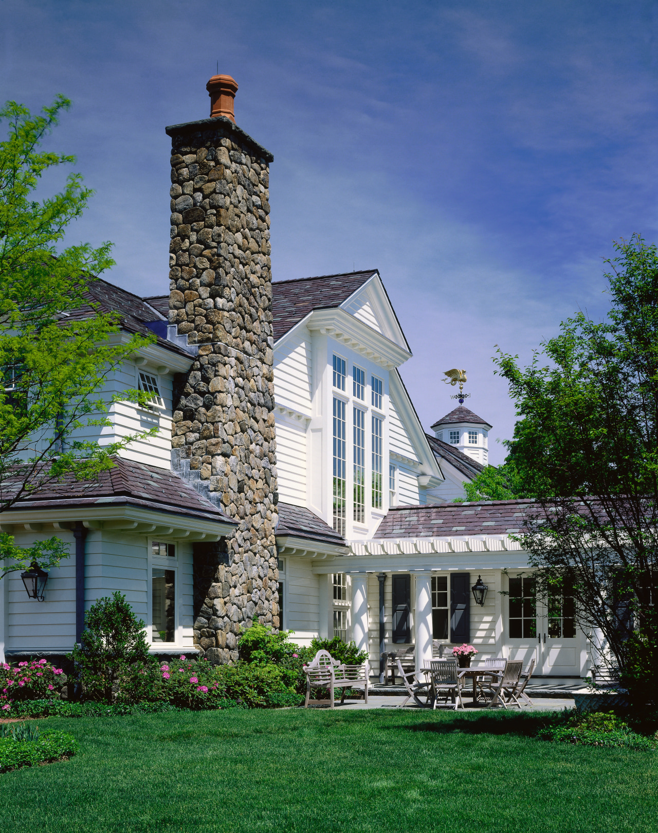 Exterior view of home with white cladding, grey architecture, building, cottage, estate, facade, farmhouse, grass, historic house, home, house, lawn, mansion, outdoor structure, property, real estate, residential area, roof, sky, tree, blue