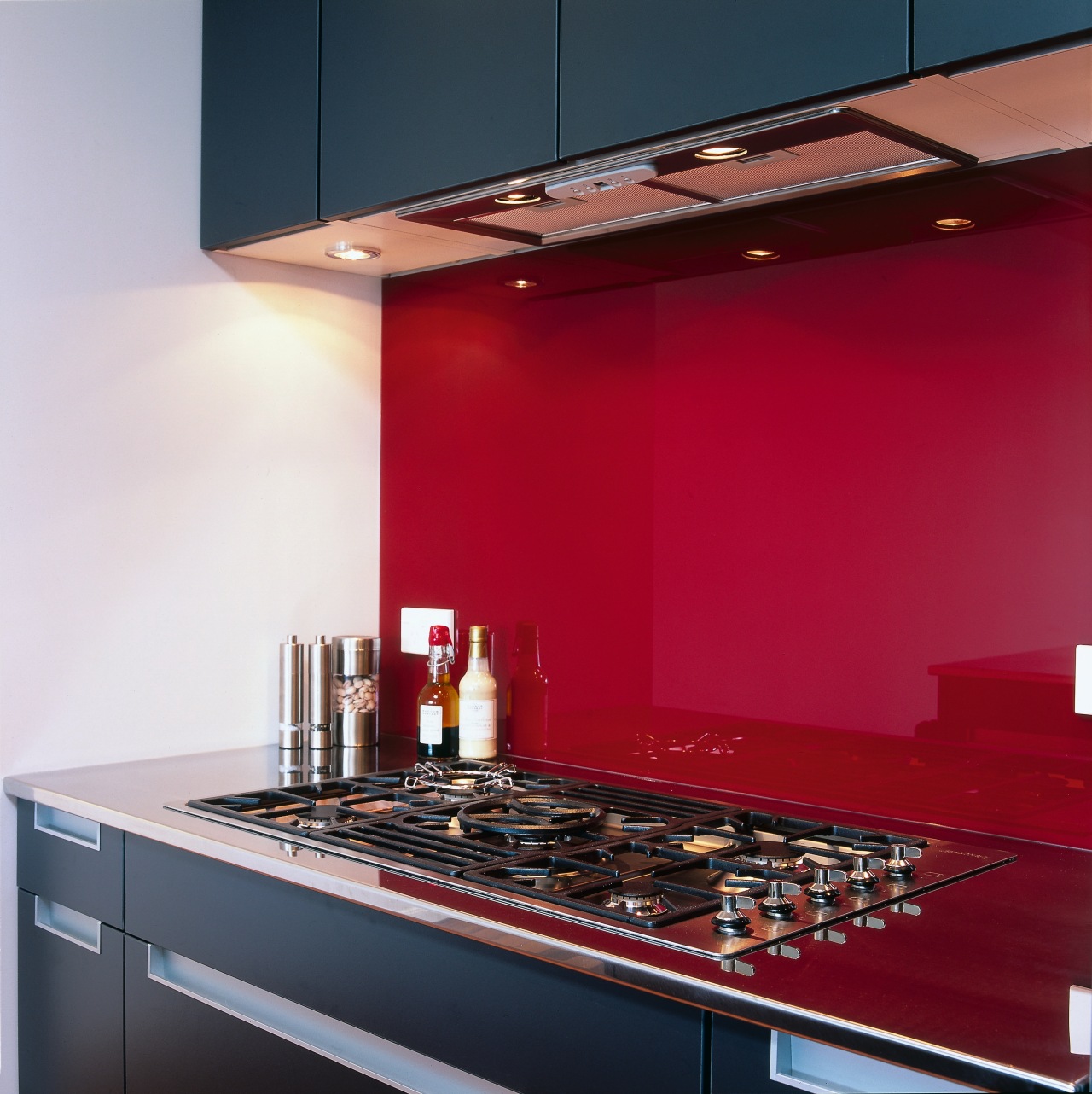 Kitchen cooktop with red splashback. ceiling, countertop, interior design, kitchen, light fixture, lighting, under cabinet lighting, red