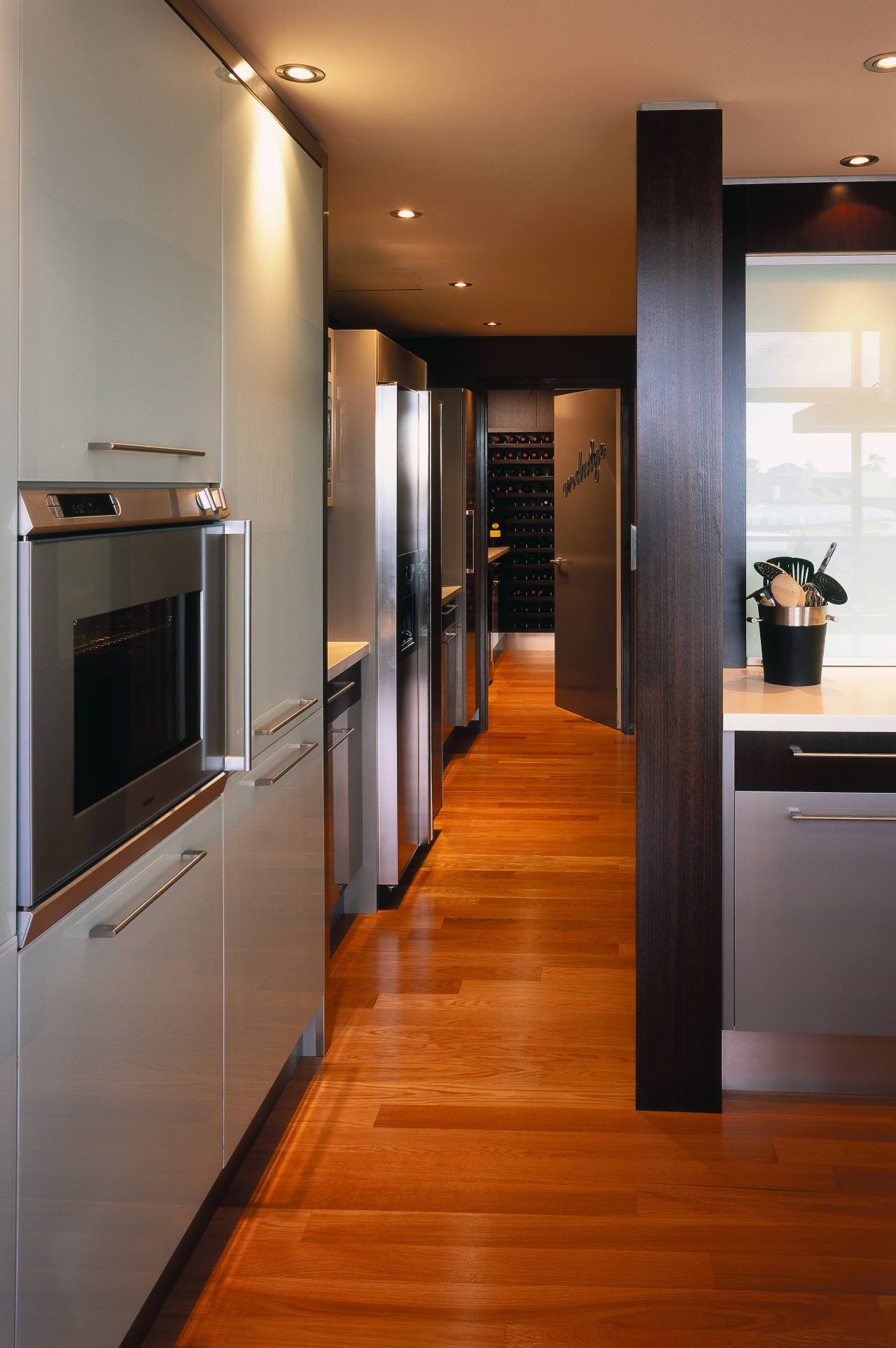 view of the kitchen featuring darkwood veneer wall, cabinetry, countertop, floor, flooring, hardwood, interior design, kitchen, laminate flooring, room, wood, wood flooring, brown