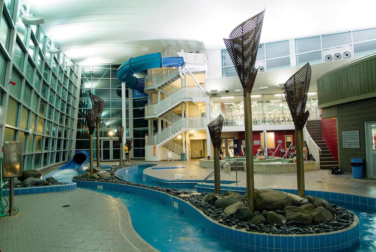 View of indoor pool complex, featuring water slide, architecture, building, condominium, leisure, leisure centre, mixed use, real estate, reflection, swimming pool, water, white