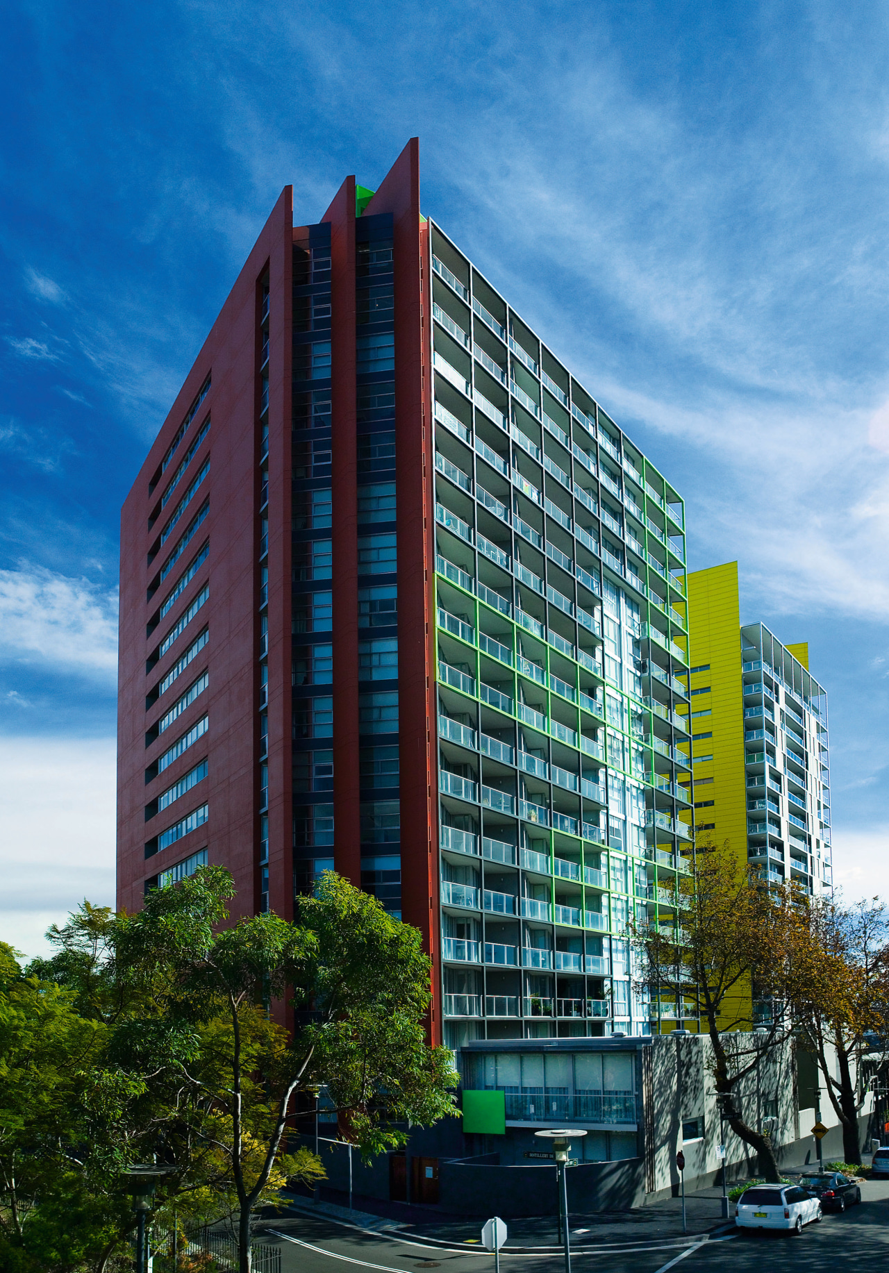 Two apartment complexes, one with red cladding, one apartment, architecture, building, city, commercial building, condominium, corporate headquarters, daytime, facade, headquarters, hotel, metropolis, metropolitan area, mixed use, real estate, residential area, sky, skyscraper, tower block, urban area, teal