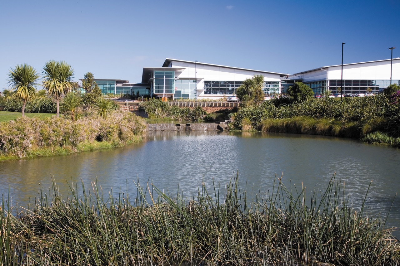 A view of the man made lake made bank, city, plant, pond, real estate, reflection, reservoir, river, sky, tree, water, water resources, waterway, wetland, teal