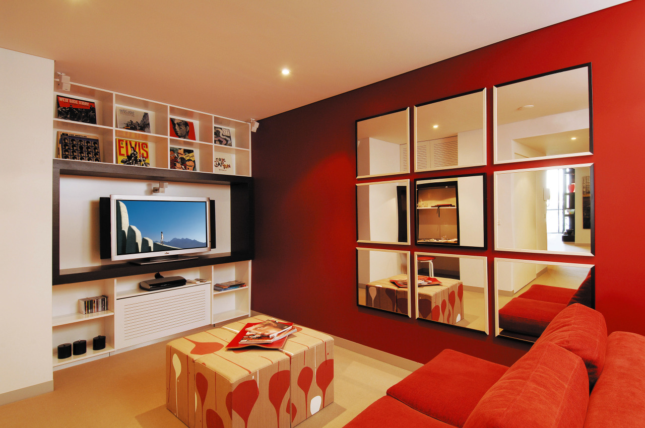 View of this living area featuring a fujitsu bookcase, cabinetry, ceiling, furniture, home, interior design, interior designer, living room, real estate, room, shelving, wall, red, orange