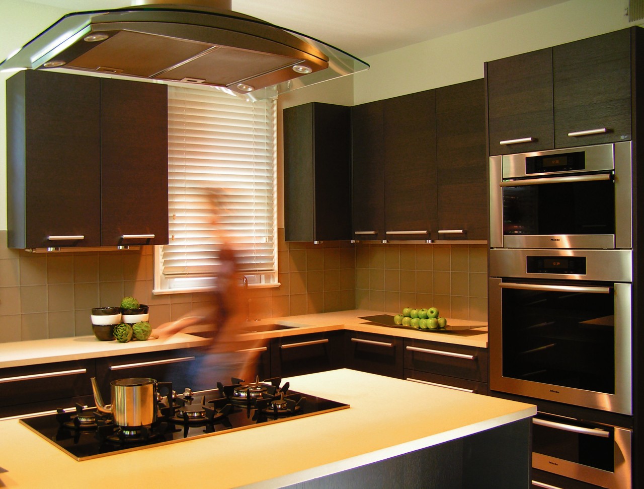 A view of this kitchen features cabinets by cabinetry, countertop, interior design, kitchen, light fixture, lighting, room, under cabinet lighting, brown