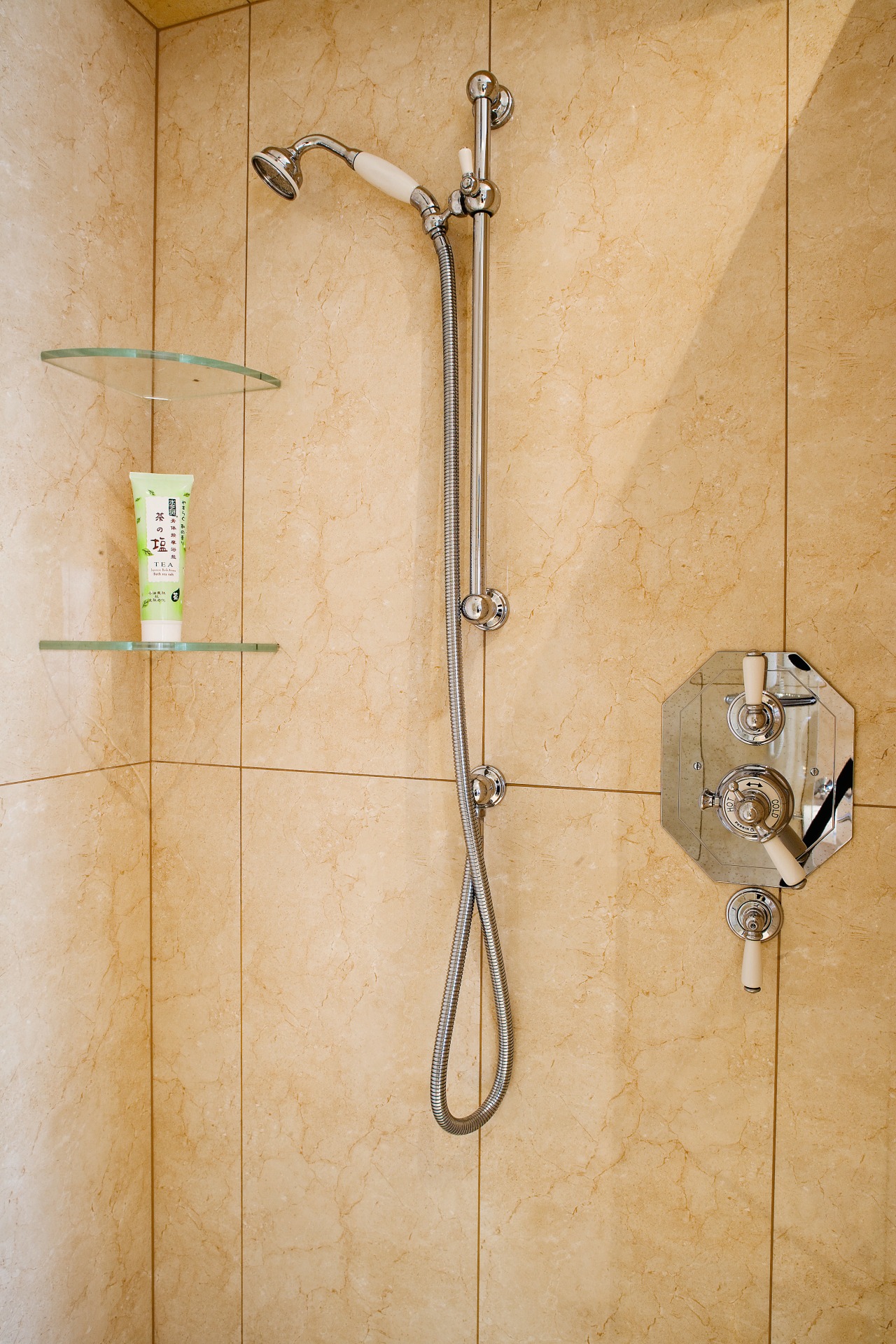 View of a tiled shower enclosure with chrome bathroom, plumbing fixture, shower, tap, tile, wall, orange