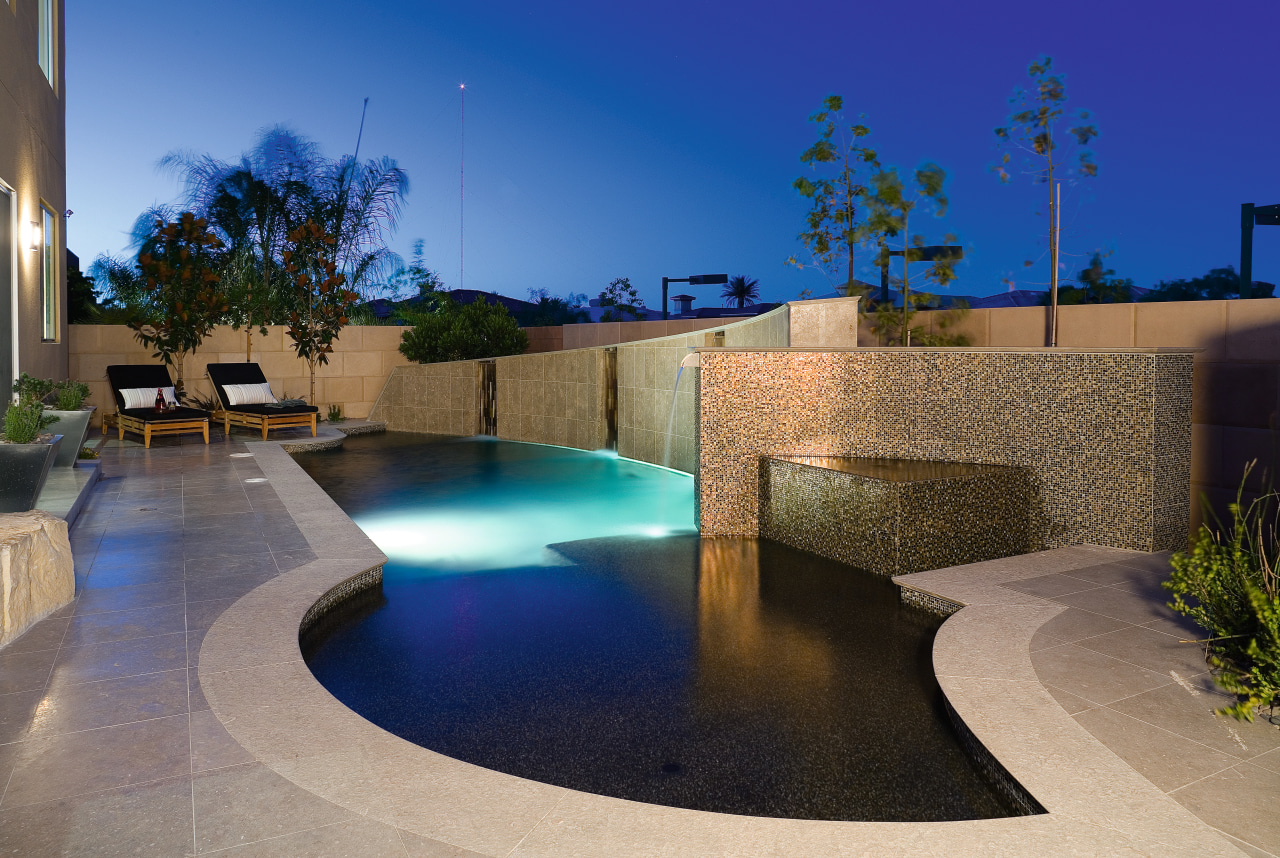 A view of this architecturallly designed pool by architecture, backyard, condominium, estate, home, house, landscape lighting, leisure, lighting, property, real estate, reflection, residential area, swimming pool, wall, water, water feature, blue