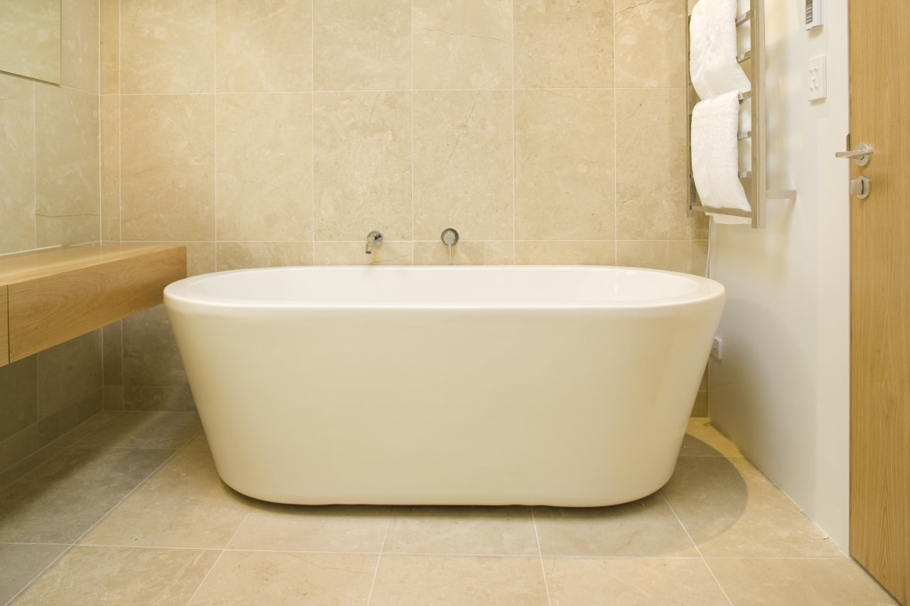 The freestanding bath functions as a piece of bathroom, bathroom sink, bathtub, ceramic, floor, flooring, interior design, plumbing fixture, product design, sink, tap, tile, toilet seat, wall, orange