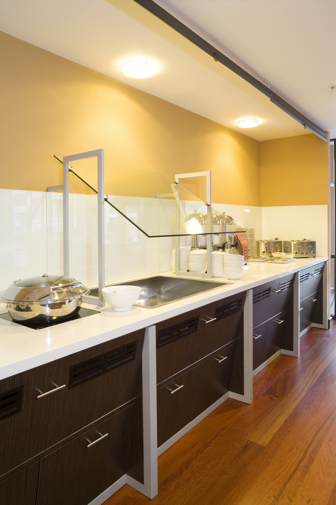 The angled design of the joinery extends to cabinetry, ceiling, countertop, cuisine classique, interior design, kitchen, room, orange, brown