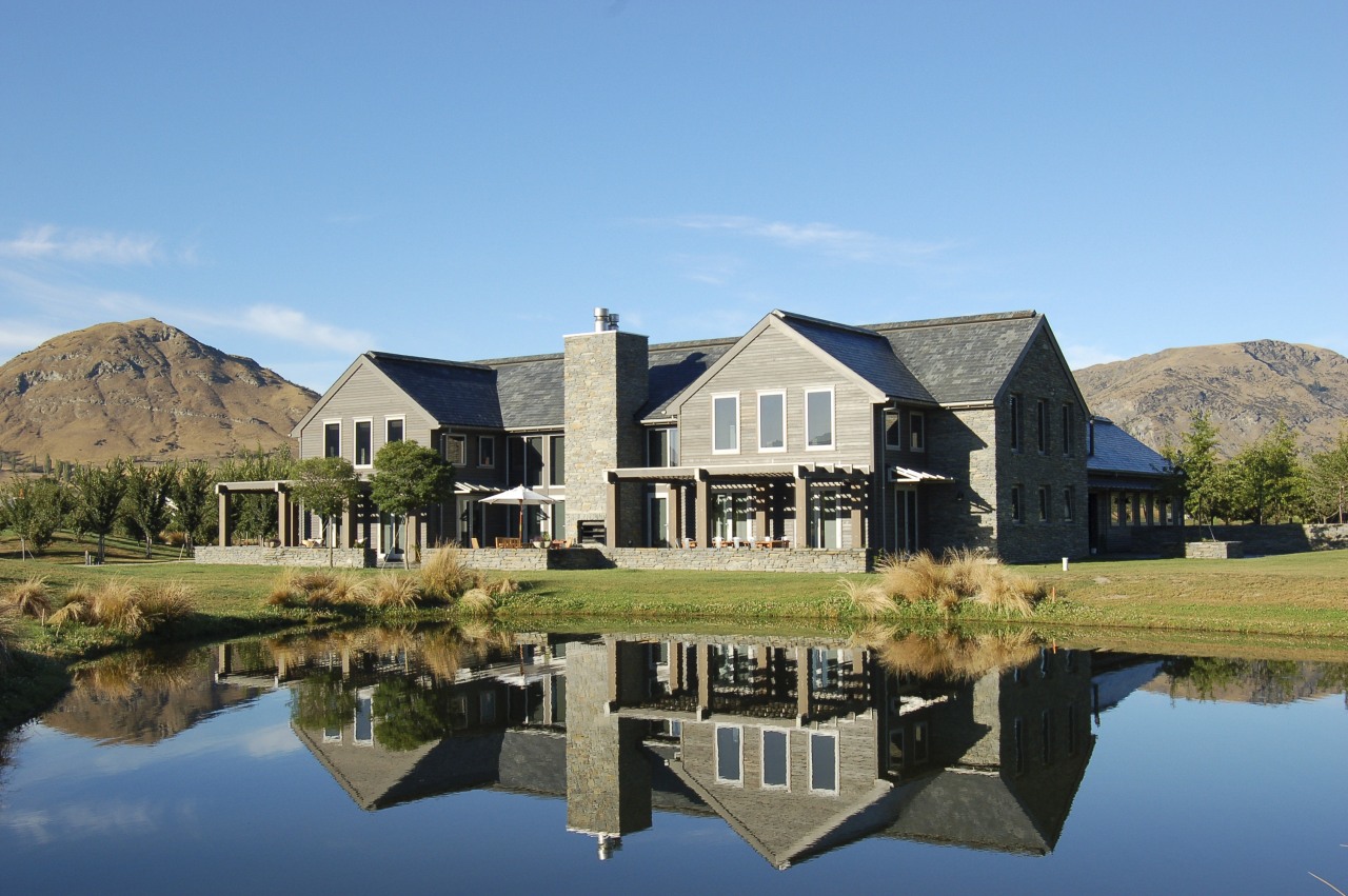 A exterior view of this queenstown lakeside home cottage, estate, farmhouse, home, house, lake, landscape, property, real estate, reflection, sky, villa, water, teal