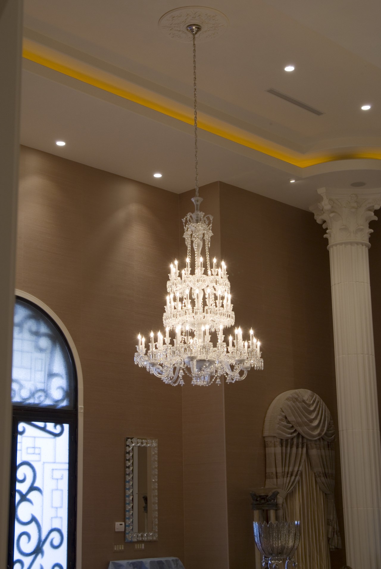 A second Baccarat chandelier hangs in the foyer. ceiling, chandelier, decor, interior design, lamp, lampshade, light fixture, lighting, lighting accessory, wall, brown