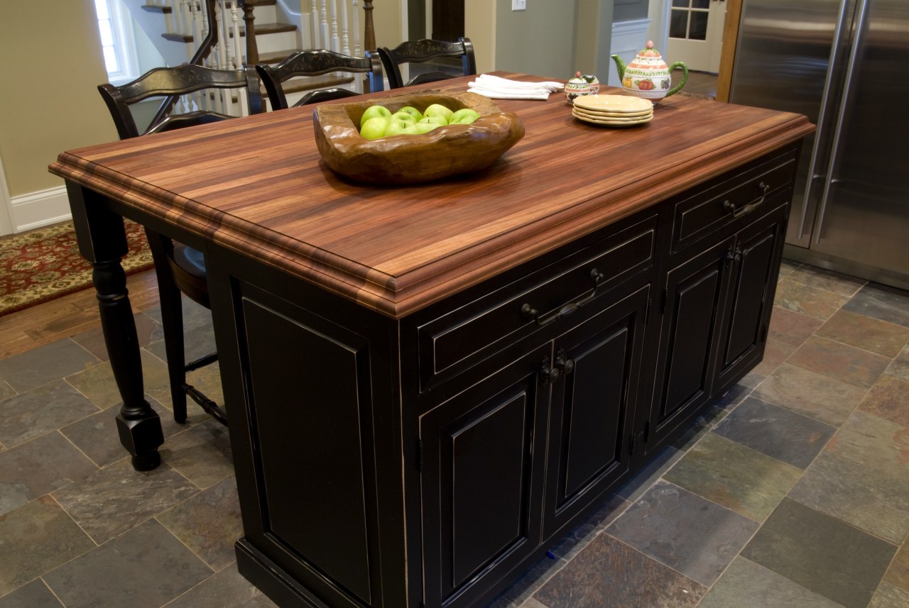 A solid mahogany countertop with black cabinetry of cabinetry, countertop, floor, flooring, furniture, hardwood, kitchen, table, tile, wood stain, black, brown