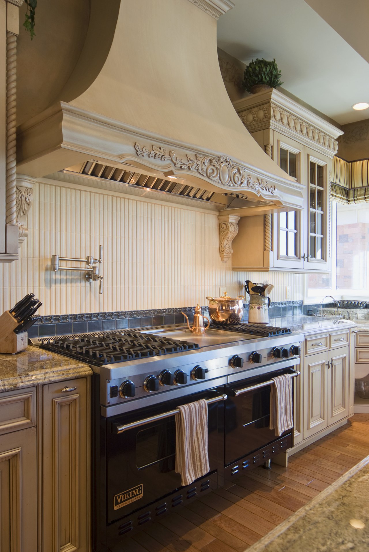 A custom-designed, French Provincial-style hood with a decorative cabinetry, countertop, cuisine classique, flooring, interior design, kitchen, brown, gray