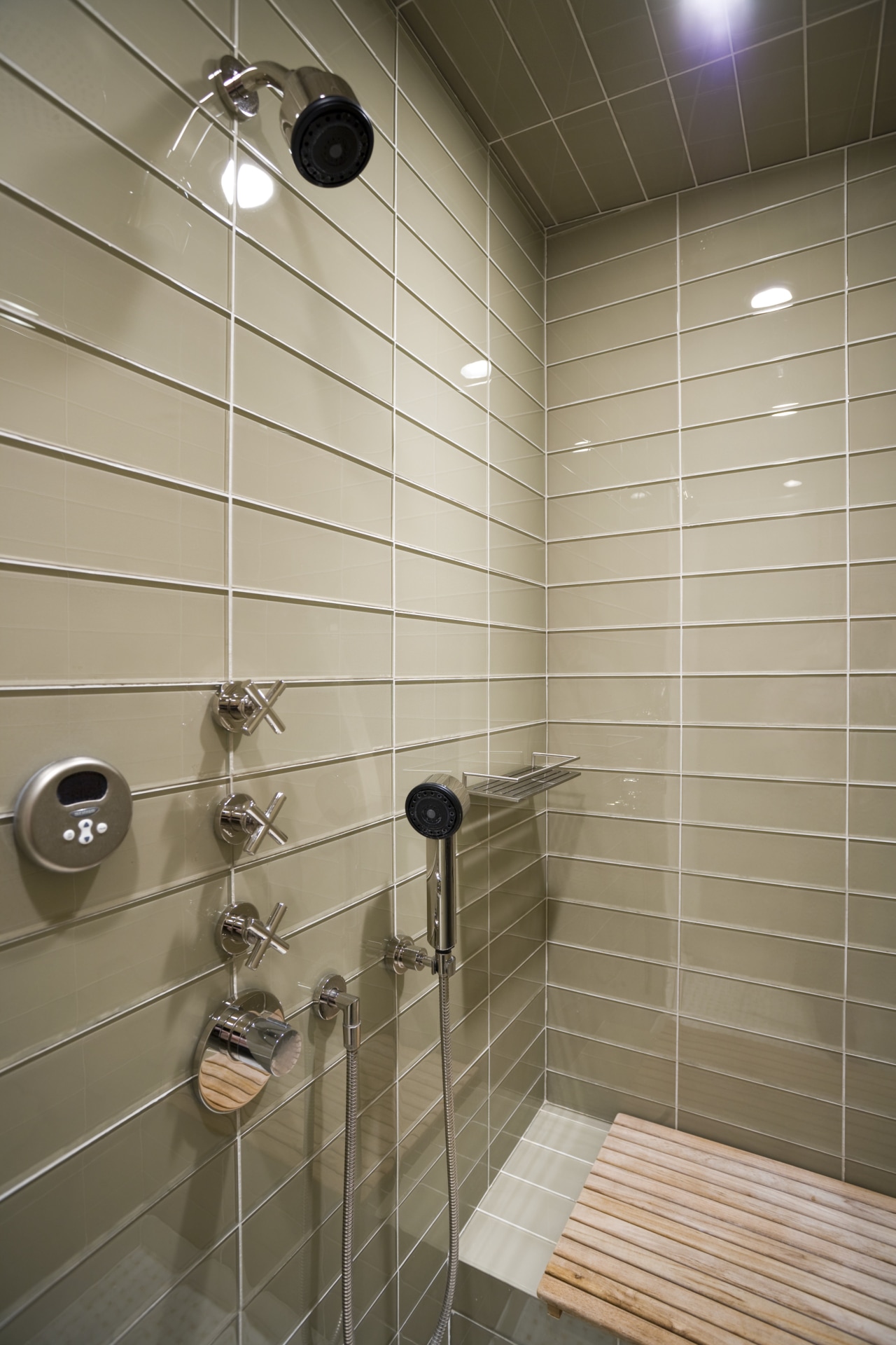 View of shower enclosure which features wall tiling, bathroom, floor, flooring, interior design, plumbing fixture, room, shower, tile, wall, gray, brown