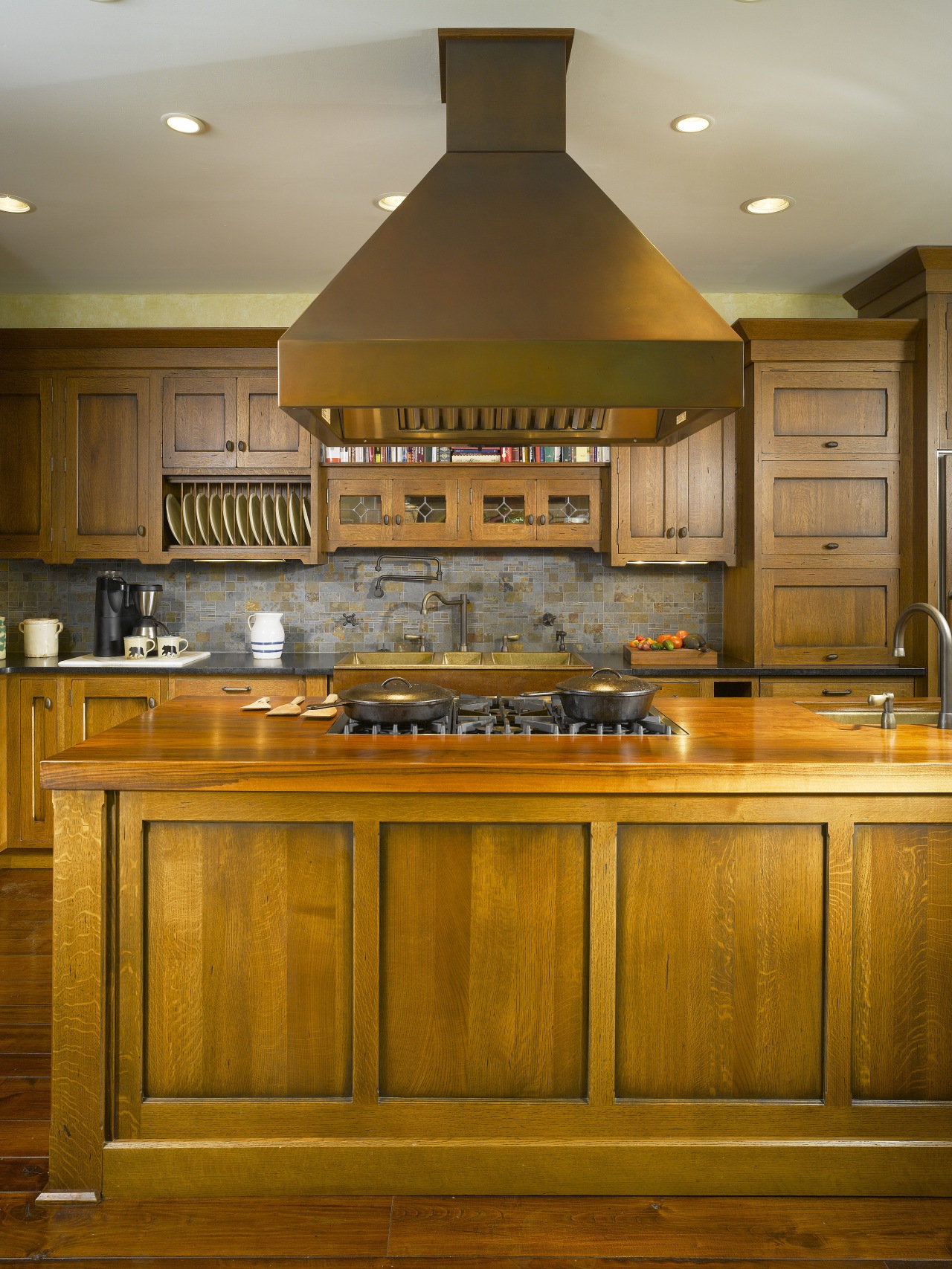 View of a kitchen which features an island cabinetry, countertop, cuisine classique, hardwood, interior design, kitchen, room, under cabinet lighting, brown, orange