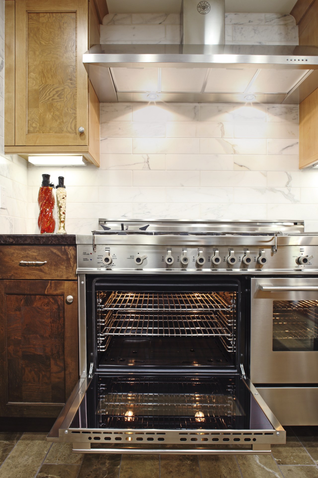 View of a contemporary kitchen which features a cabinetry, countertop, floor, flooring, home appliance, interior design, kitchen, kitchen appliance, kitchen stove, oven, tile, white, brown