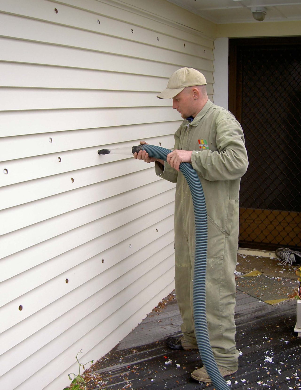 Qmulus BIB dry-fibre insulation being installed by an floor, outdoor structure, roof, siding, standing, window, wood, white