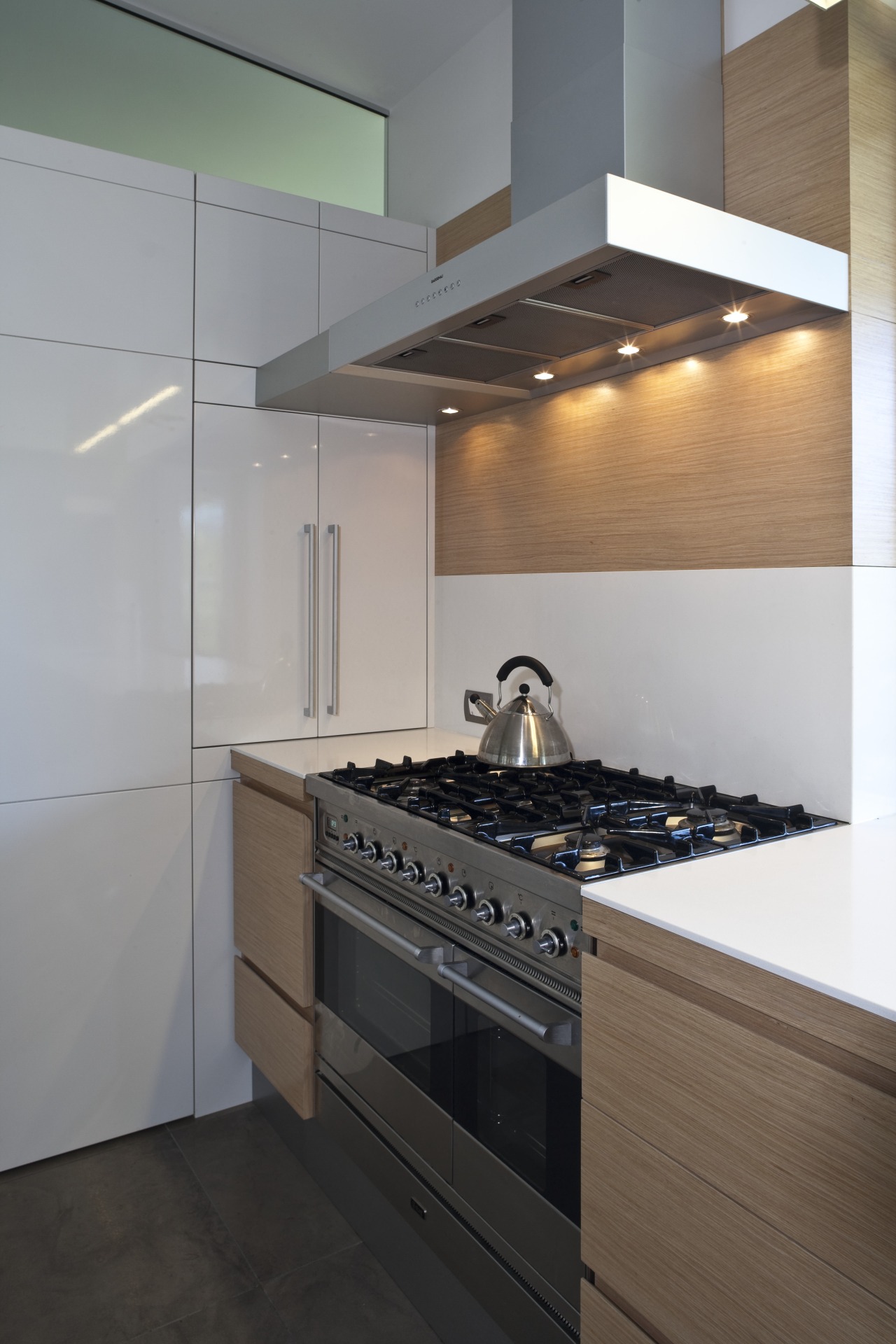 View of kitchen and living area featuring light cabinetry, countertop, home appliance, interior design, kitchen, kitchen stove, room, gray