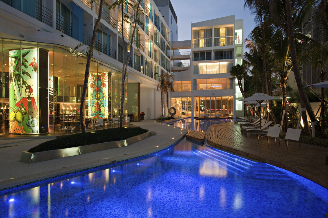 View of outdoor pool and lounge area. building, condominium, estate, home, hotel, leisure, mixed use, night, property, real estate, reflection, resort, swimming pool, water, black, blue