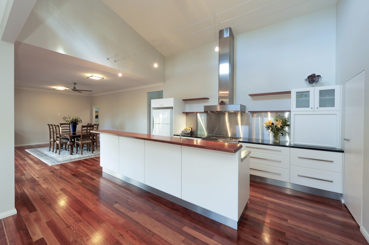 View of the kitchen area which features stainless cabinetry, ceiling, countertop, estate, floor, flooring, hardwood, interior design, kitchen, laminate flooring, property, real estate, room, wood, wood flooring, gray, red