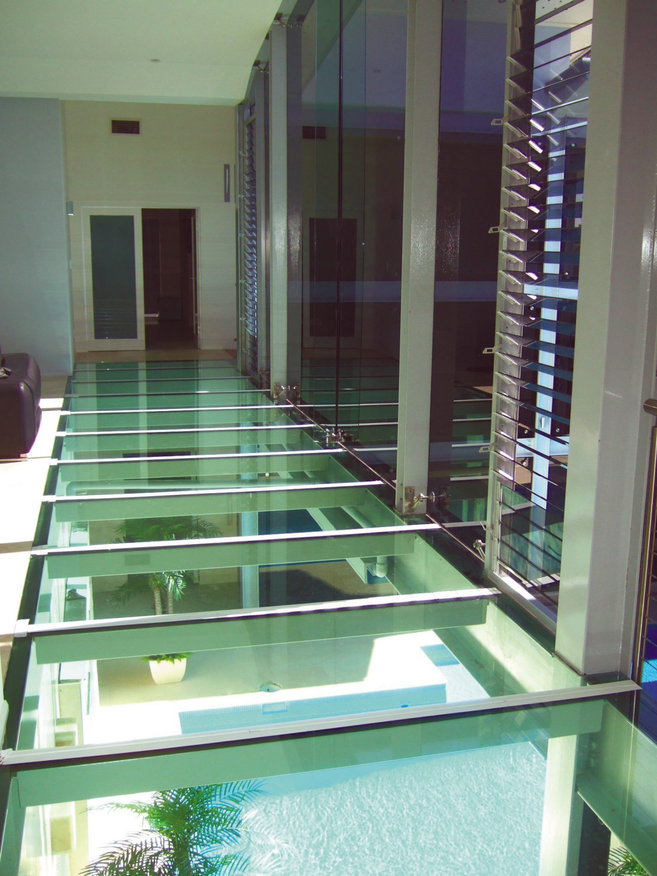 view of a glass bridge which stretches over condominium, floor, flooring, glass, gray