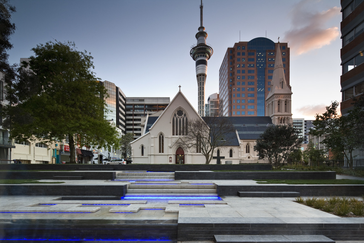 View of St Patrick's square featuring landscaping, paving, building, city, condominium, daytime, downtown, landmark, metropolitan area, neighbourhood, plaza, real estate, reflection, sky, tree, urban area, water, gray, black