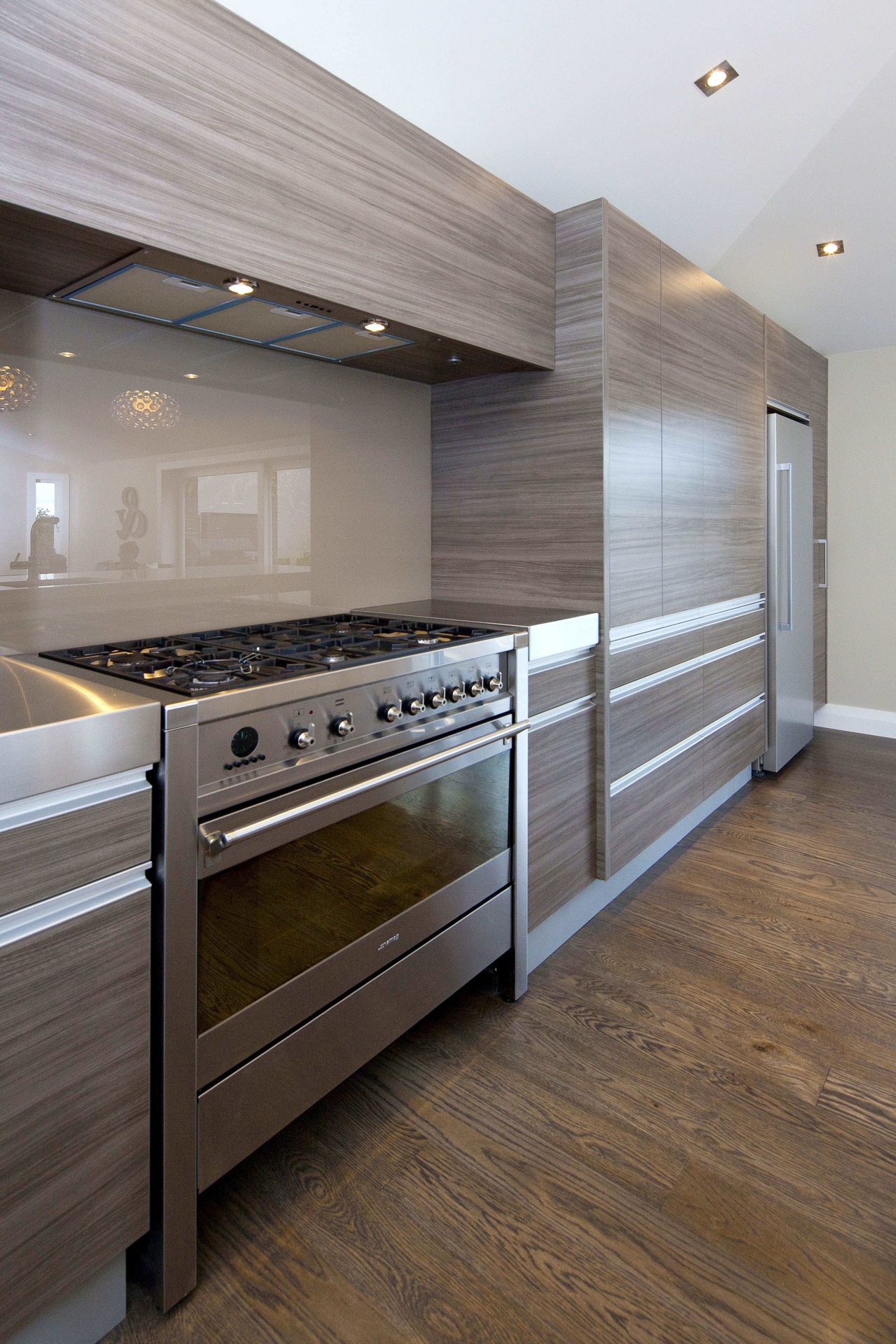 View of a kitchen which features white CeasarStone cabinetry, countertop, floor, flooring, hardwood, home appliance, kitchen, room, wood, wood flooring, gray