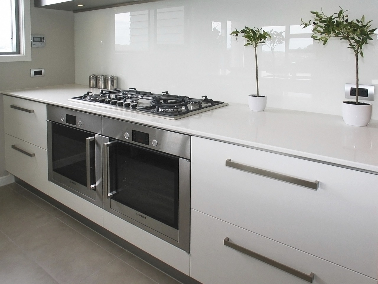 View of a kitchen which was designed by countertop, cuisine classique, gas stove, home appliance, kitchen, kitchen appliance, kitchen stove, major appliance, gray, white