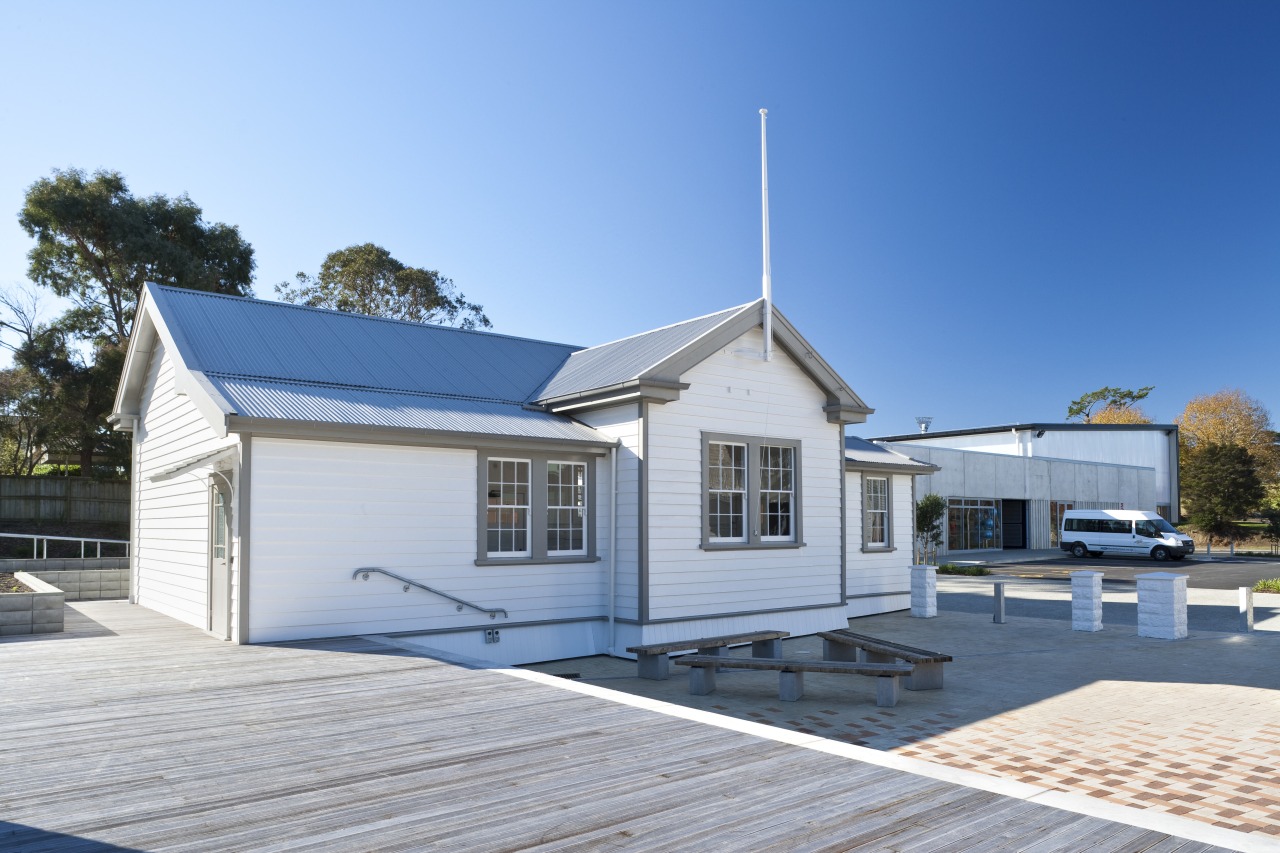 Exterior view of this educational building site cottage, facade, home, house, property, real estate, roof, siding, sky, teal