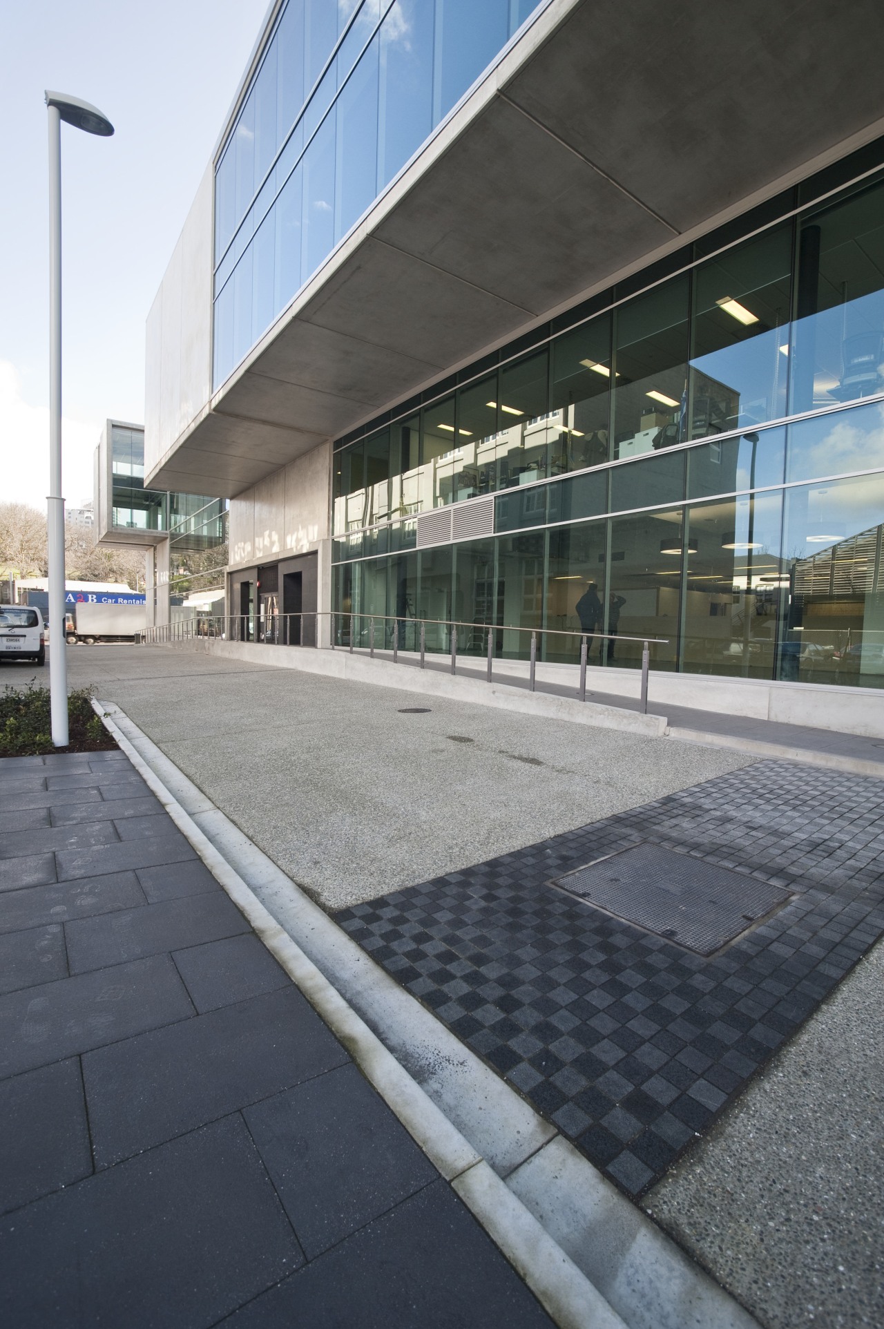 View of the entrance way to a contemporary architecture, building, commercial building, corporate headquarters, facade, glass, headquarters, line, residential area, sky, structure, black, gray