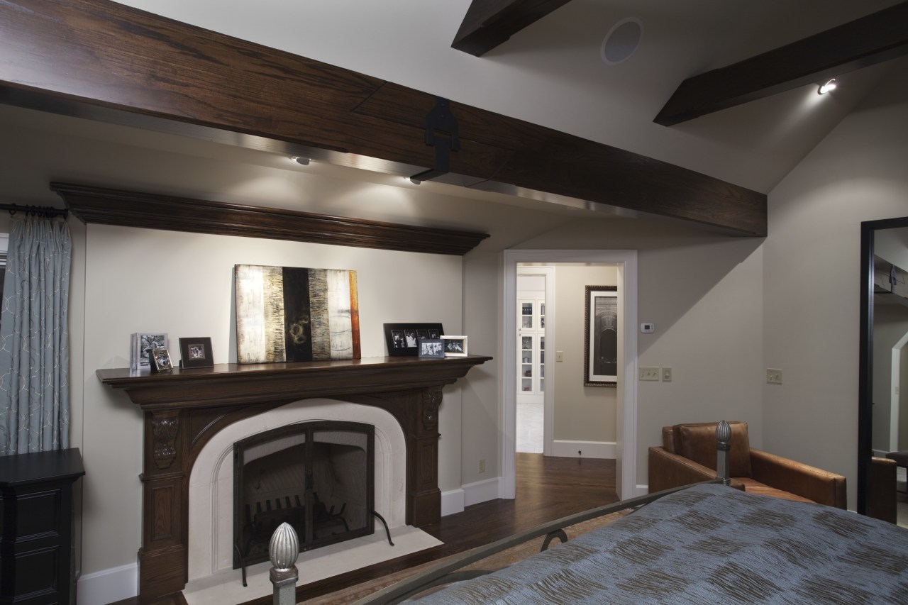 View of home with Tudor-style elements, wood fireplace beam, ceiling, fireplace, floor, flooring, hearth, home, interior design, living room, property, real estate, room, gray, black