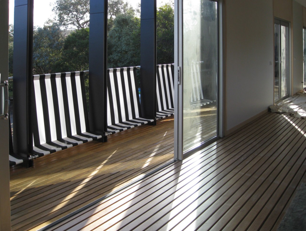 View of doorway out to balcony. deck, door, floor, flooring, hardwood, house, outdoor structure, porch, property, real estate, siding, window, wood, wood flooring, black