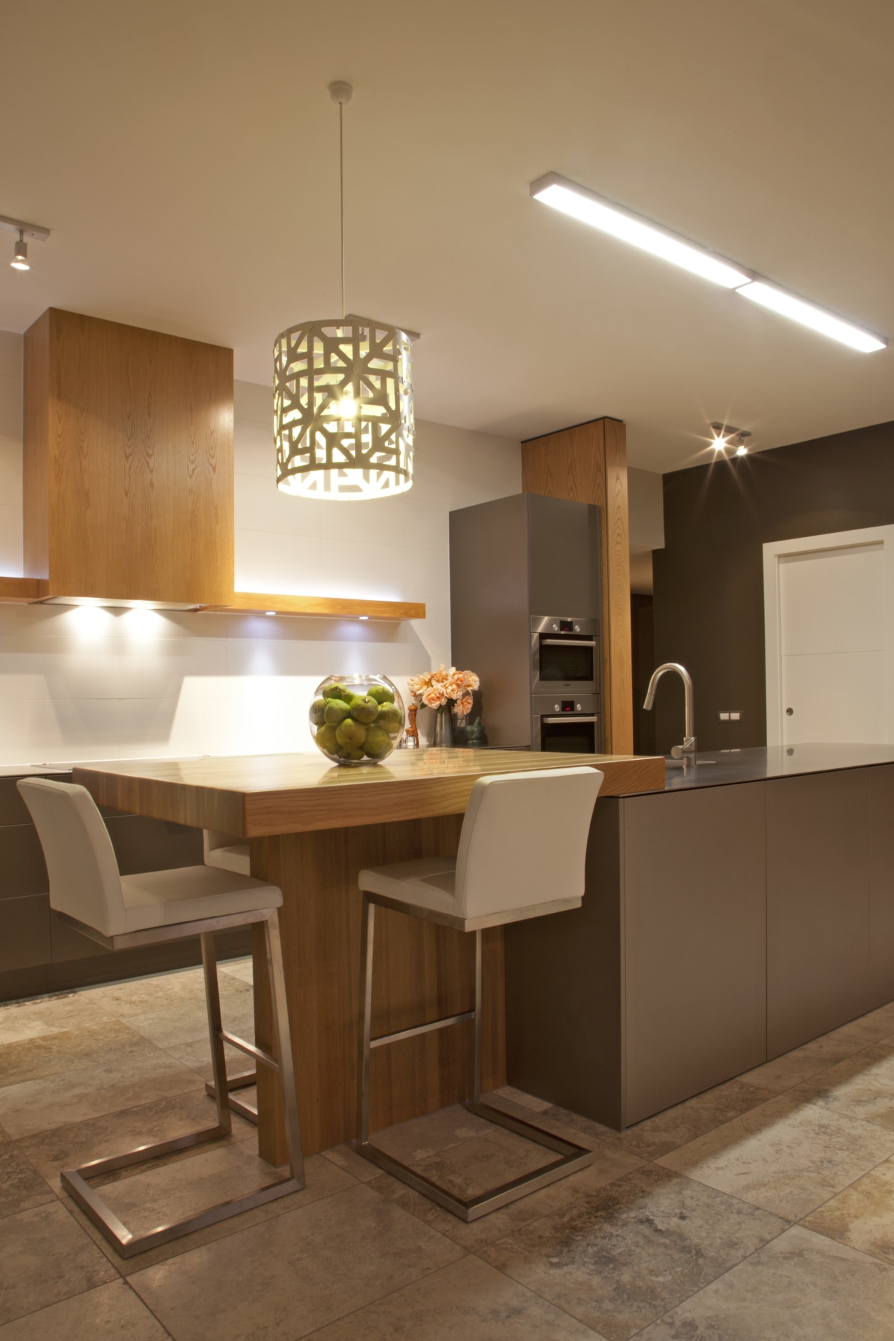 The David Trubridge lamp above this breakfast bar cabinetry, ceiling, countertop, cuisine classique, furniture, interior design, kitchen, light fixture, lighting, table, brown, orange