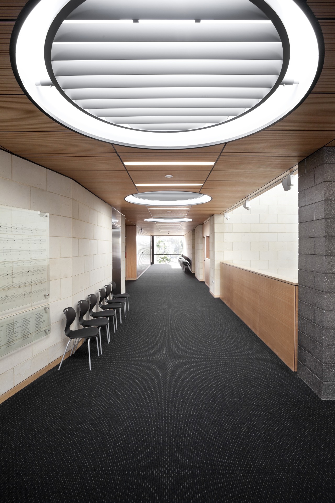 Interior with round light feature and grey carpeting. architecture, ceiling, daylighting, floor, interior design, lobby, black, white